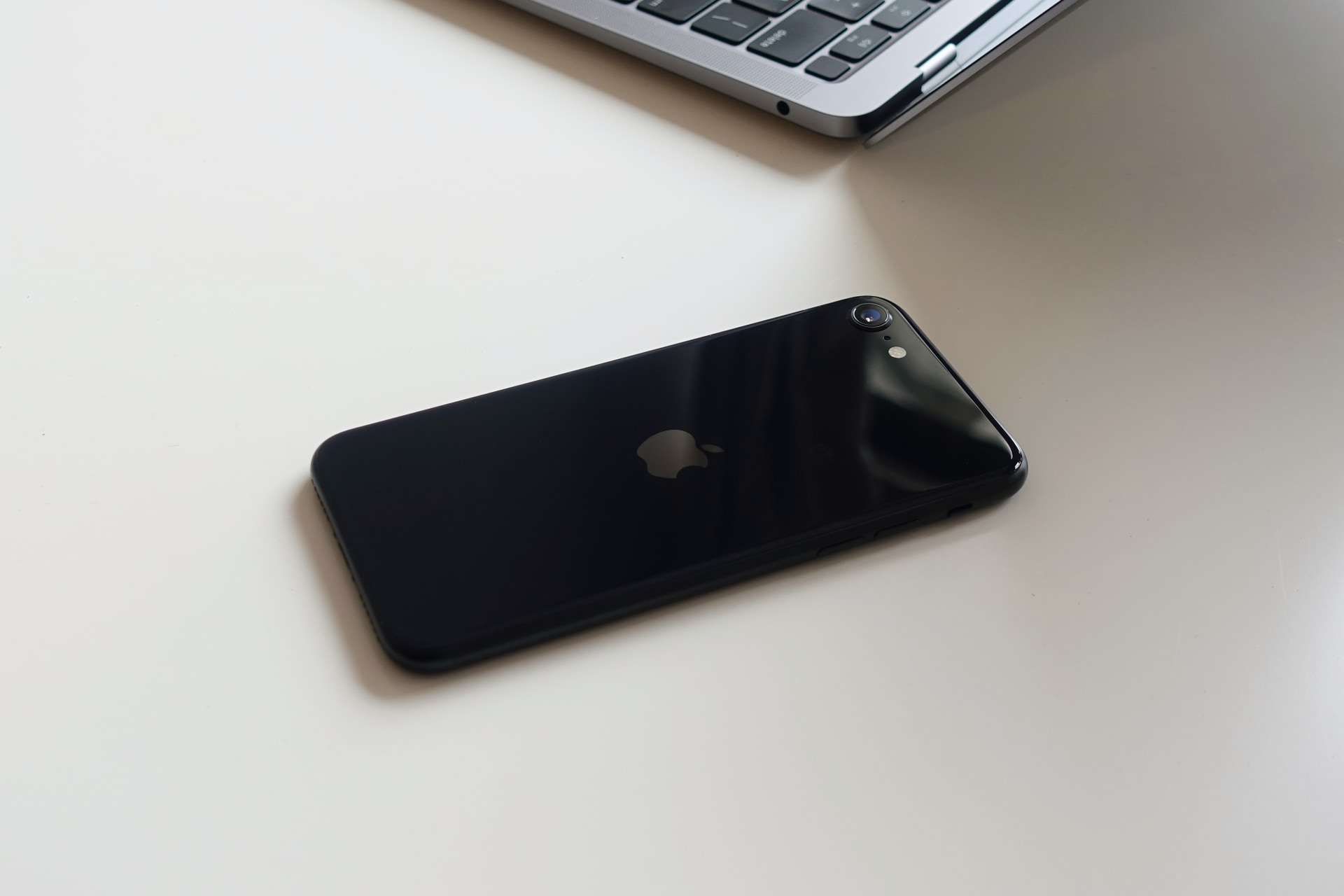 A black iPhone SE on a white table.