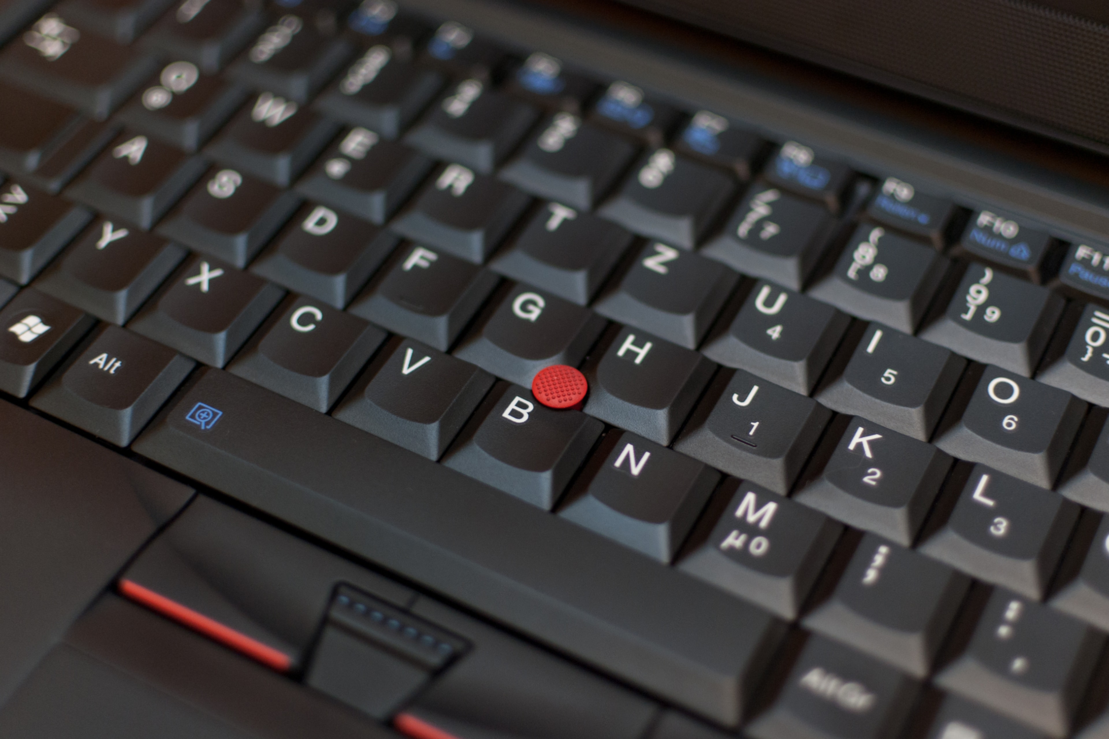 Picture of a ThinkPad laptop's keyboard showing its red Trackpoint.